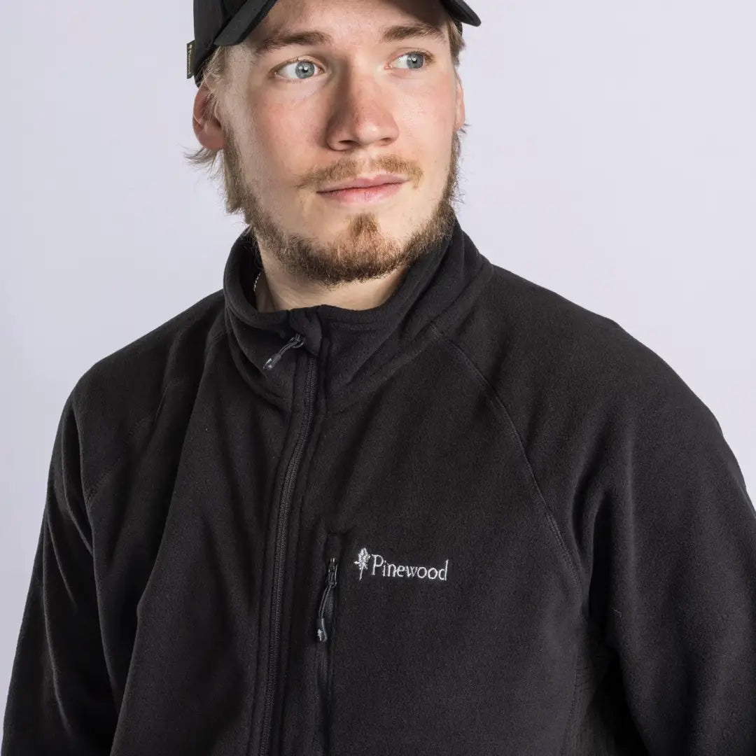 Man in a black Pinewood Air Vent Fleece Jacket and baseball cap looking stylish