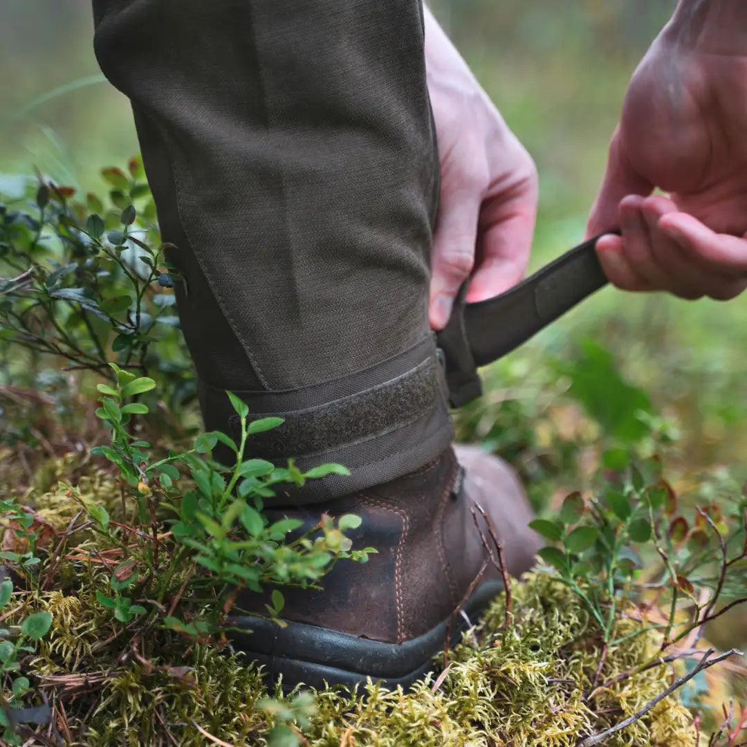 Adjusting a leather hiking boot strap for outdoor hunting with Pinewood Caribou Hunt Trousers