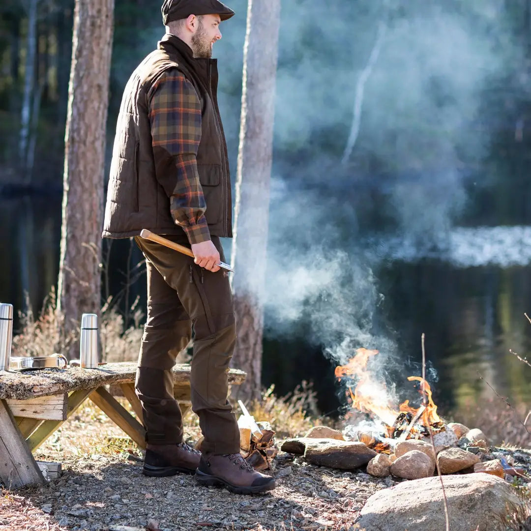 Man by a campfire in Pinewood Caribou Hunt Trousers, perfect for country clothing and hunting