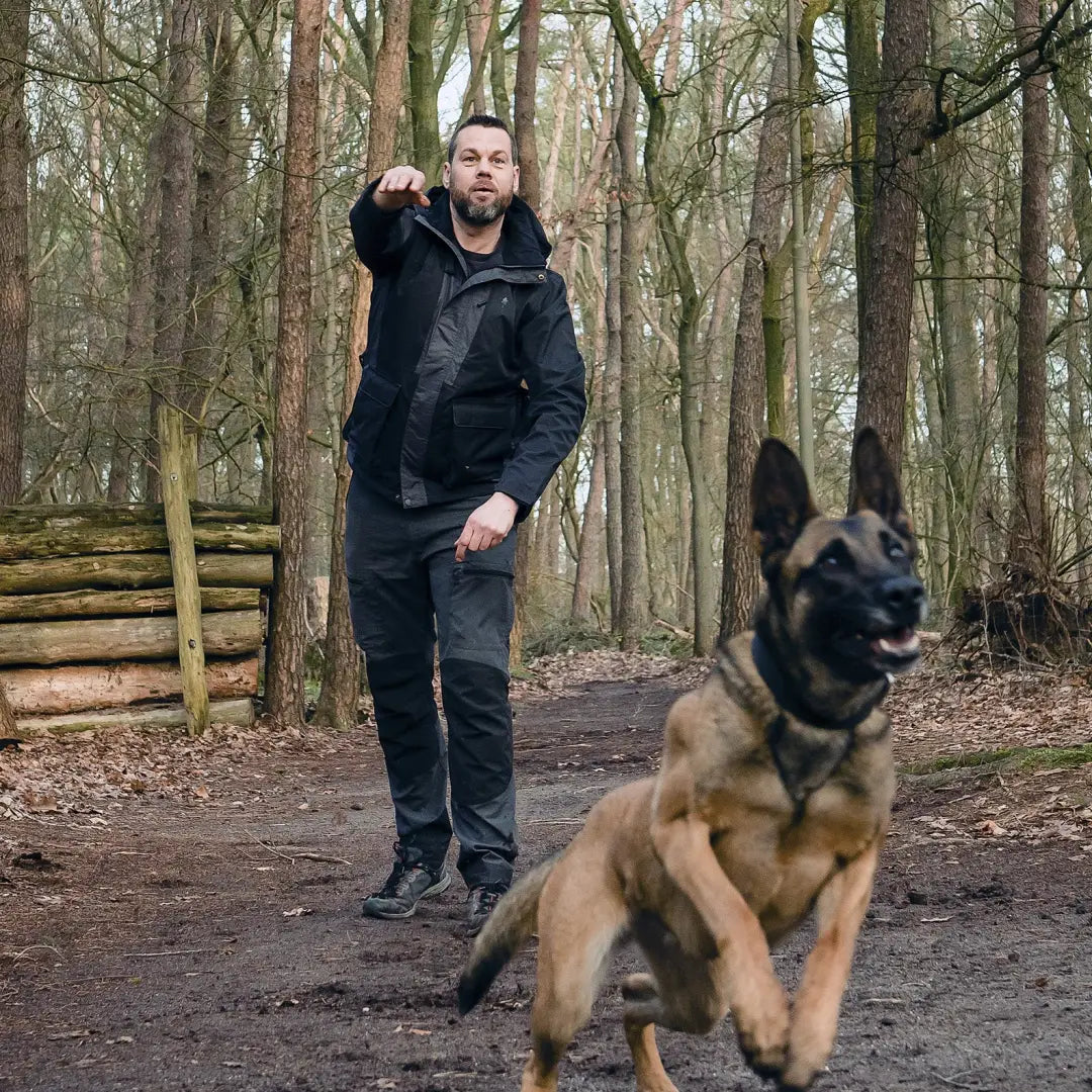 Man in Pinewood Caribou TC Men’s Trousers walking German Shepherd in forest setting