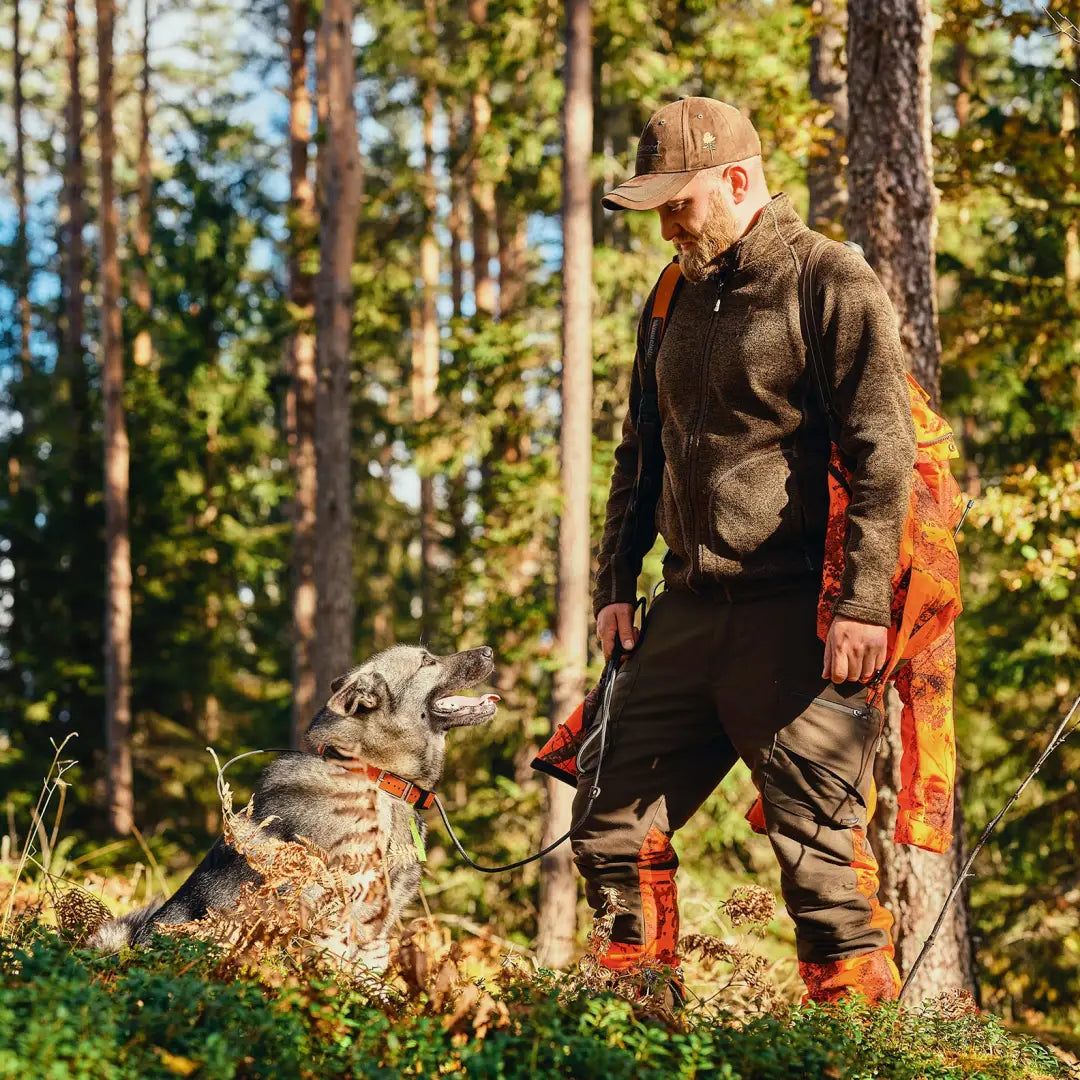 Man in Pinewood Gabriel Knitted Jacket with wolf-like dog in a cozy forest setting