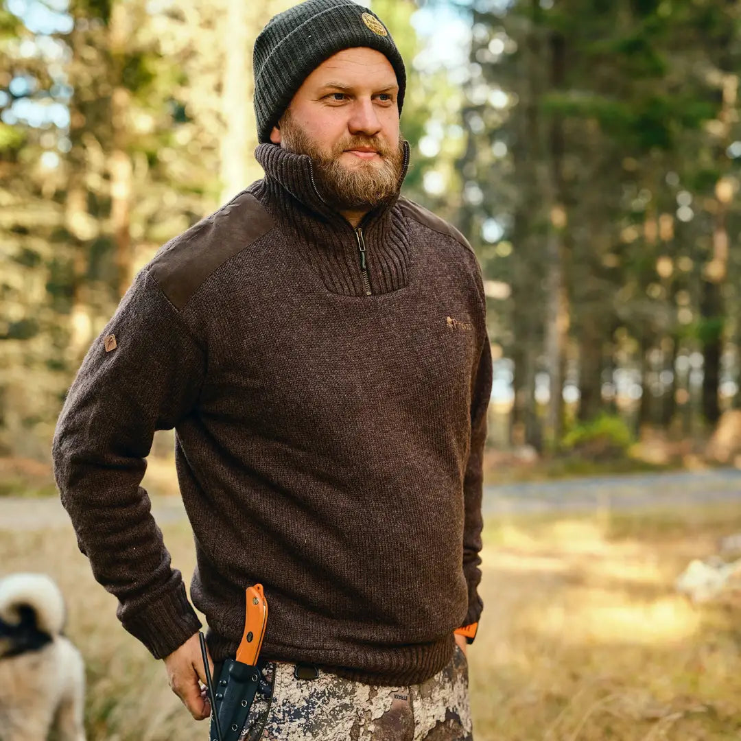 Bearded guy in a dark brown windproof sweater with high collar, chilling in the forest