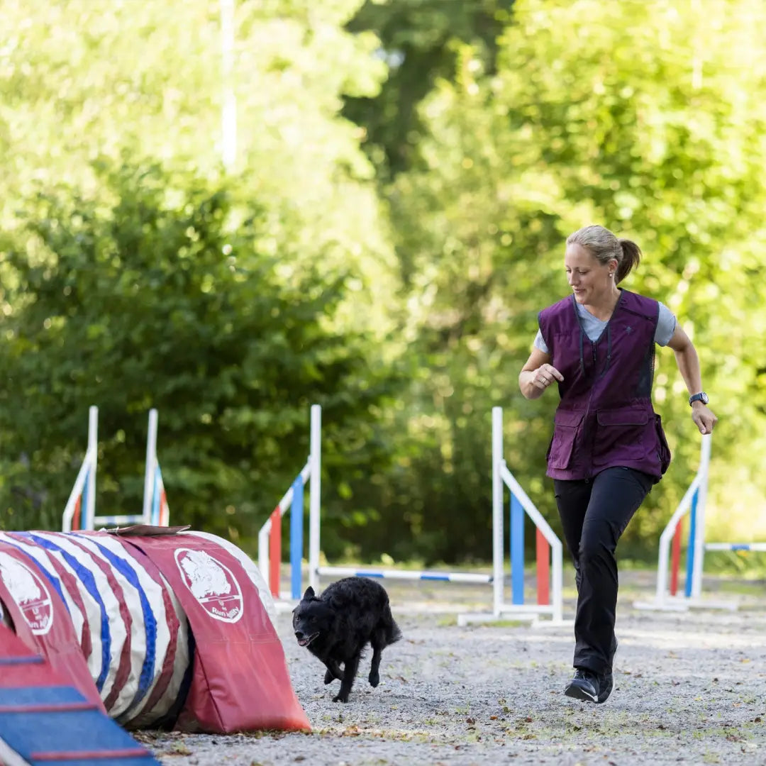 Woman in Pinewood Ladies Dog Sport Vest 2.0 running with black dog in agility course