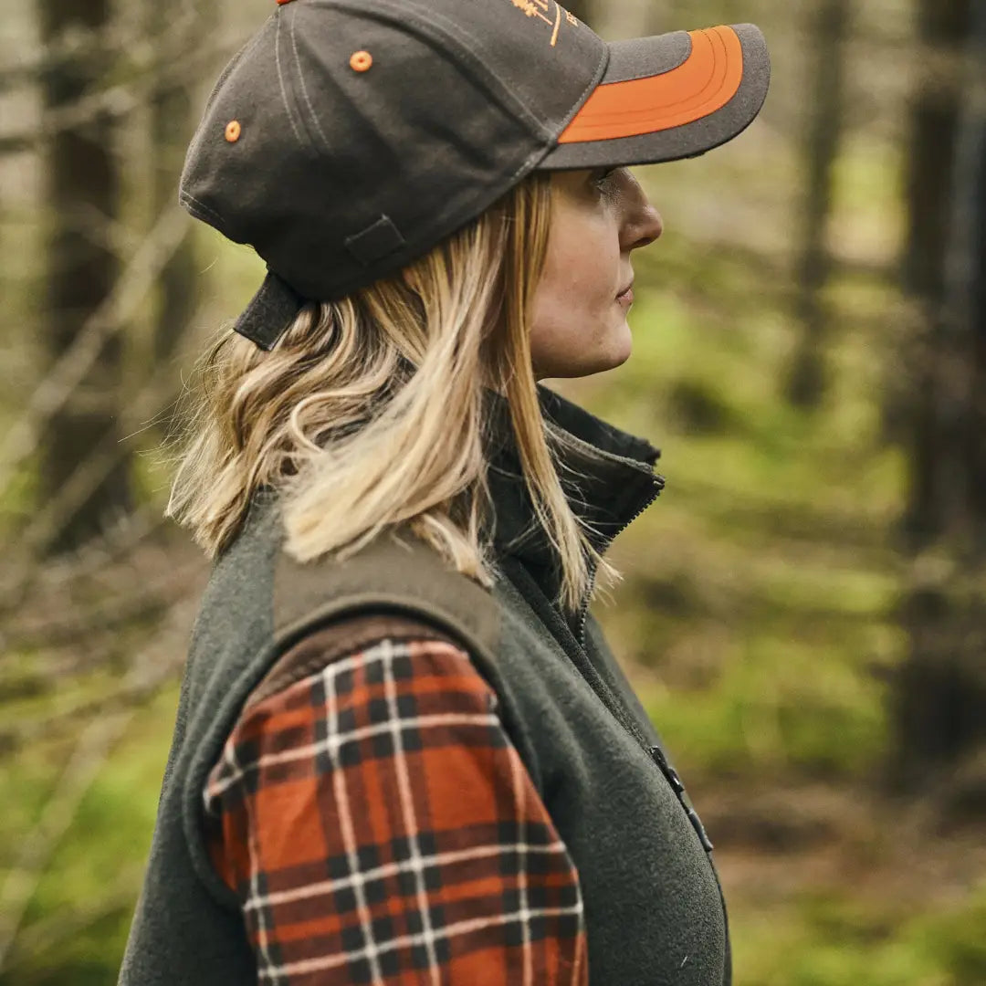 Woman in a baseball cap and plaid flannel enjoying the outdoors in country clothing