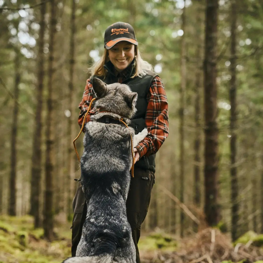 Person hugging a gray dog in the forest, perfect for country clothing lovers