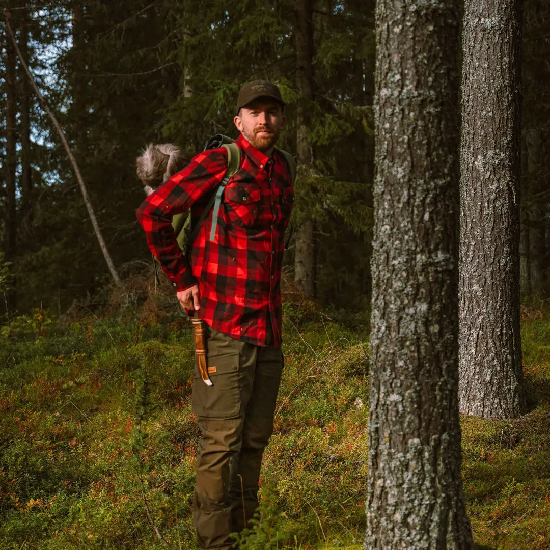 Man in a red and black plaid Pinewood Lumbo Shirt standing in a forest