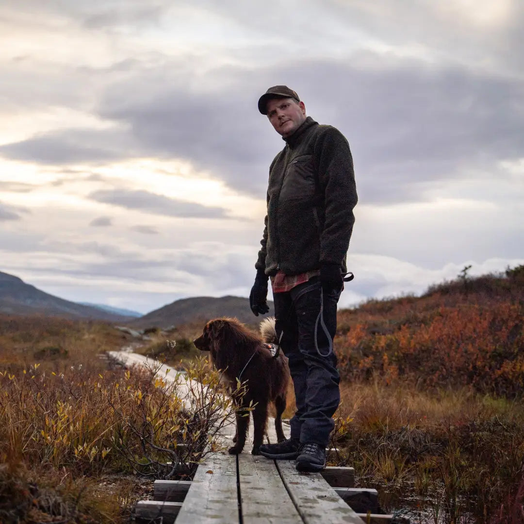 Person on a wooden walkway wearing a Pinewood Pile Fleece Jacket with a dog in nature