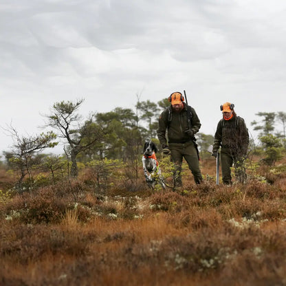 Two hunters in a field with rifles and a hunting dog wearing Pinewood Retriever Active jacket