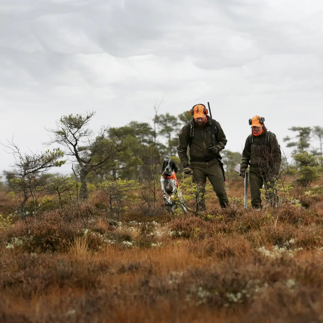 Hunters in a field with rifles and a dog wearing the Pinewood Retriever Active Ladies Hunting Jacket