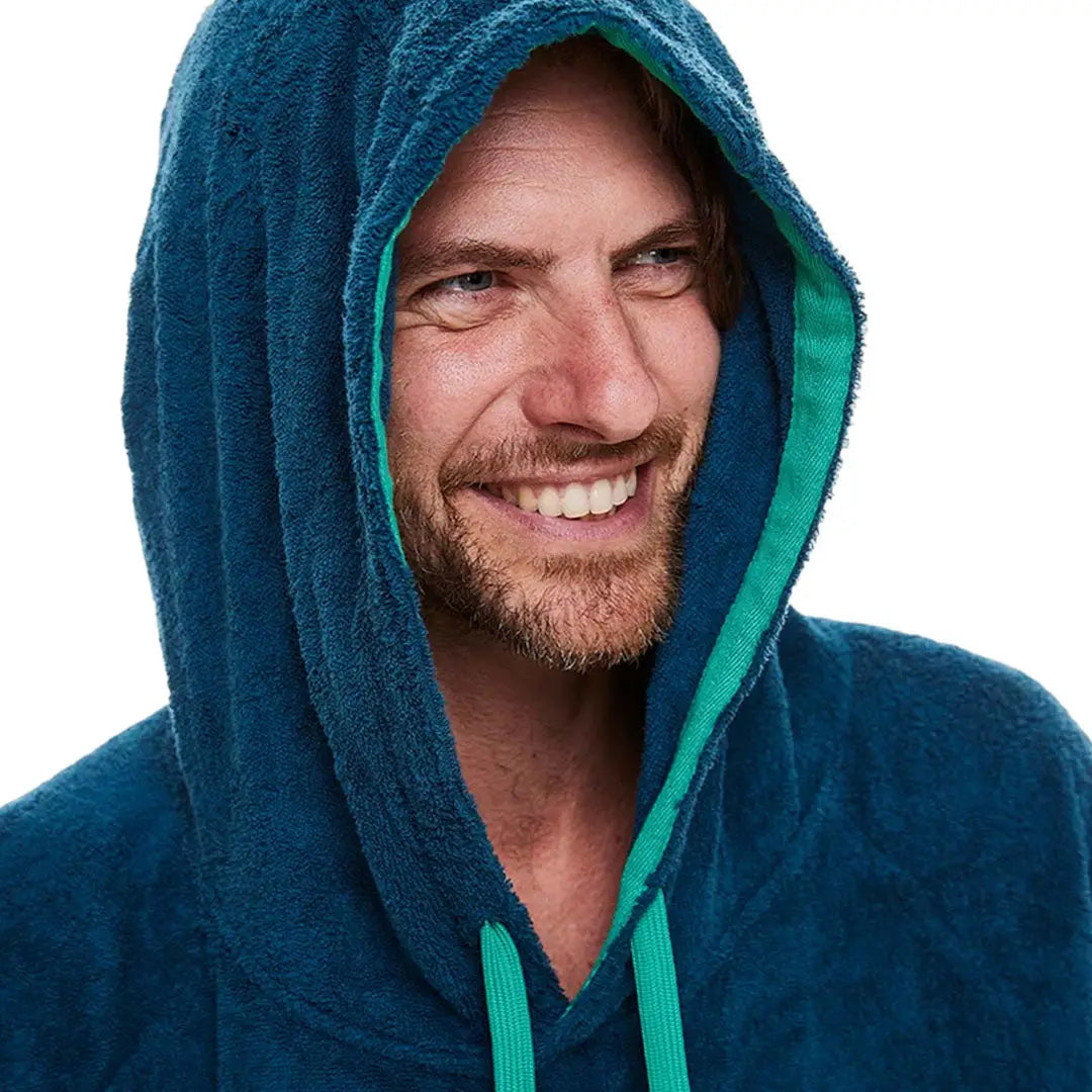 Smiling man in blue hooded sweatshirt showcasing a luxury poncho towel robe