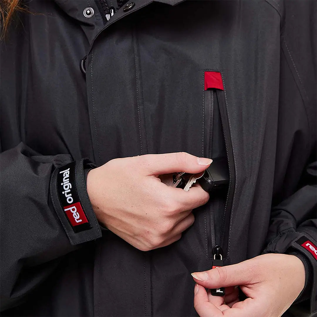 Hands opening a Red Pro Change Long Sleeve Evo Jacket with zippered pockets and red accents