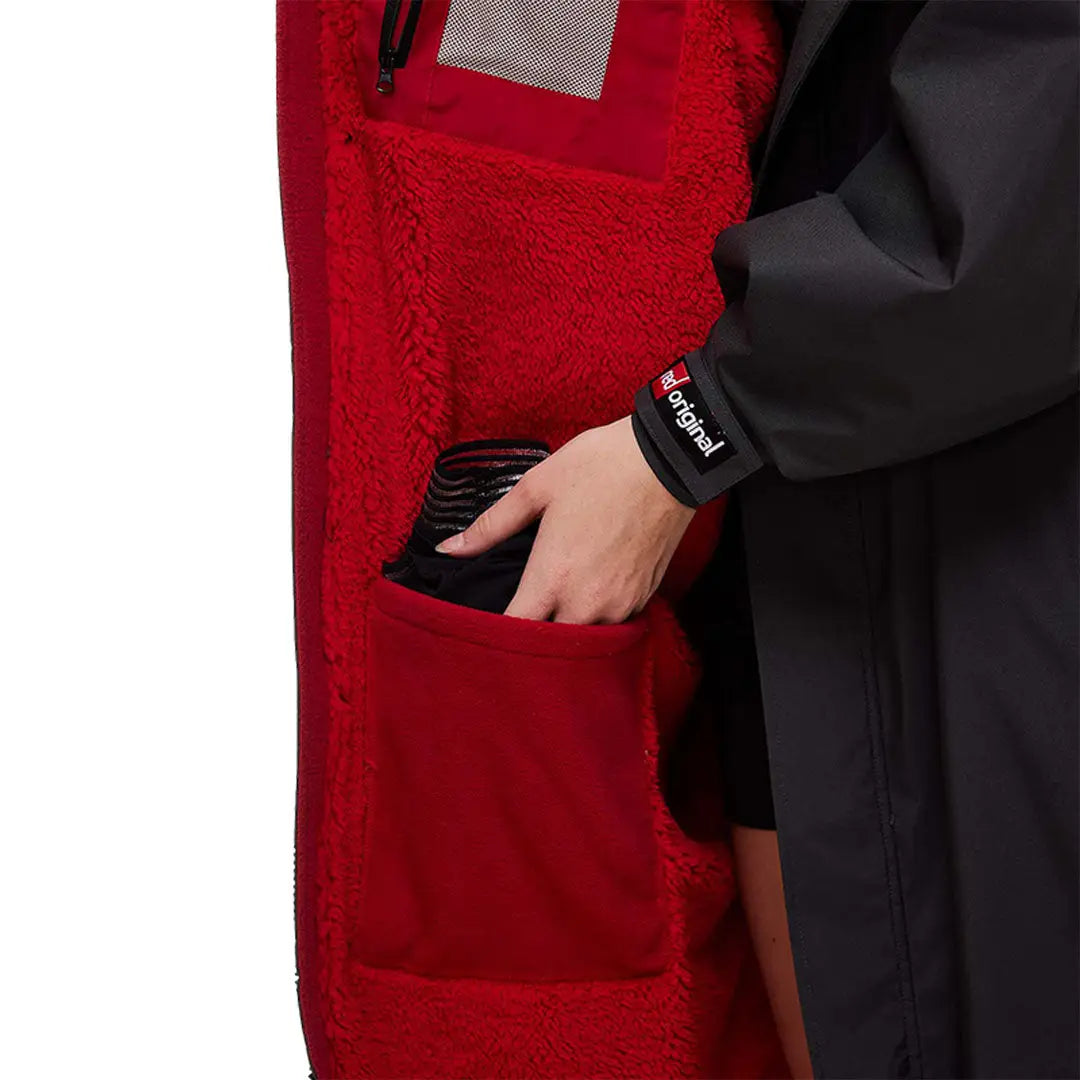 Hand in an Apple Watch reaching into a pocket of the Red Pro Change Long Sleeve Evo Jacket