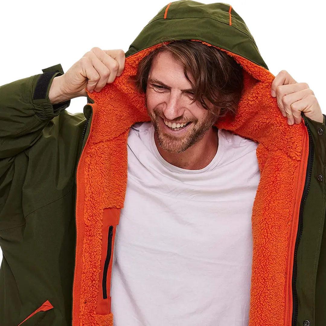 User pulling on a Green jacket with orange fleece, showcasing the Red Pro Change Long Sleeve Evo Jacket