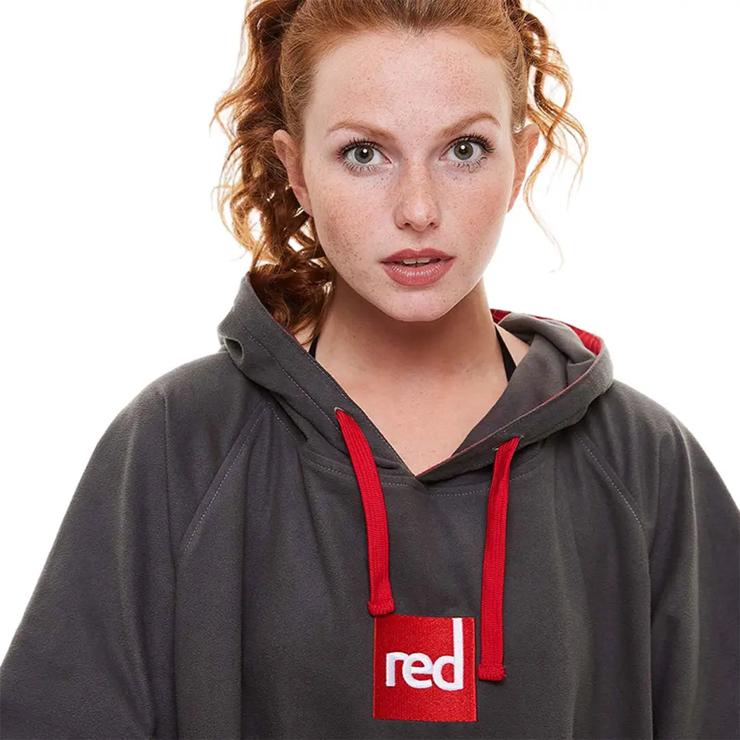 Woman with curly red hair in a gray microfibre changing robe with red details