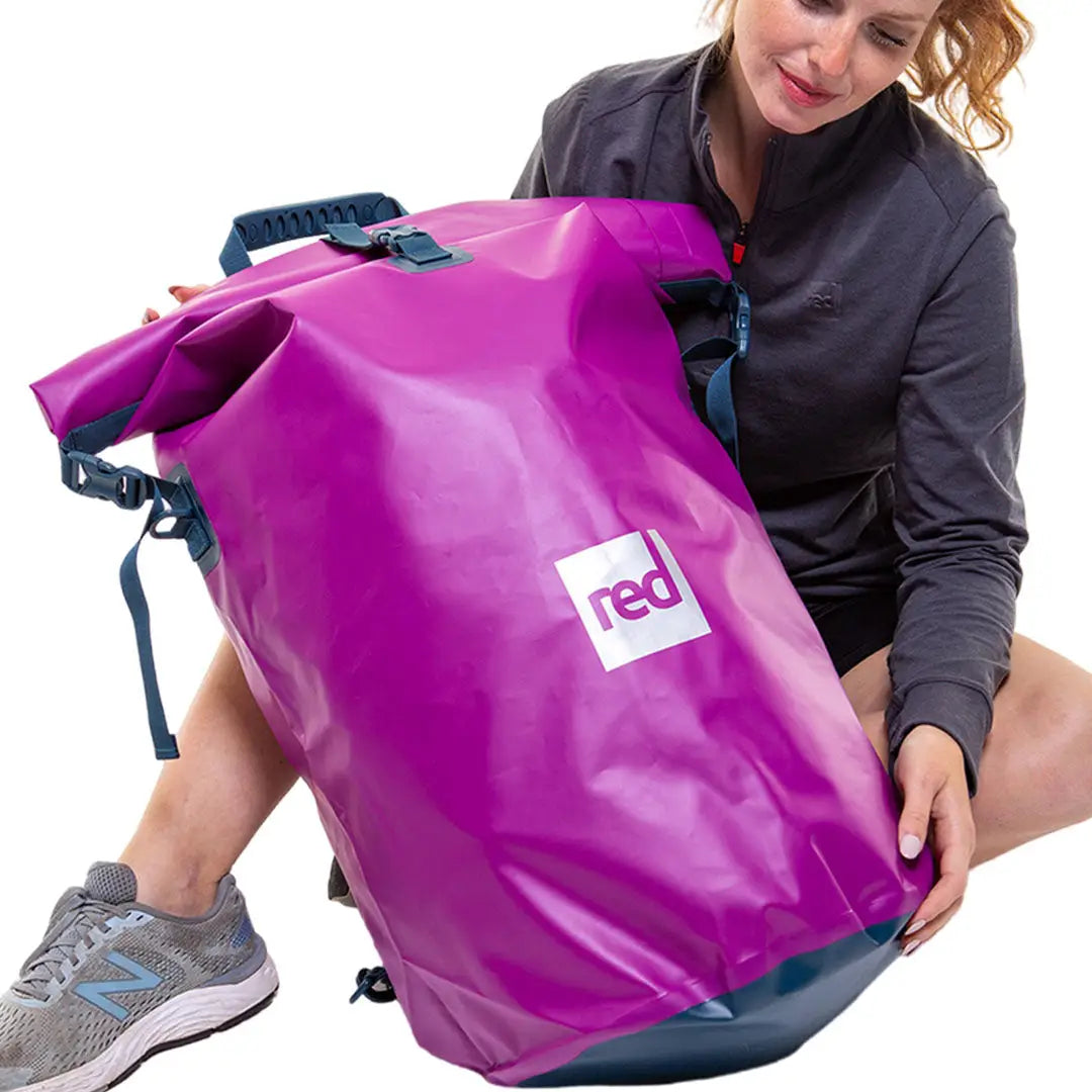 Bright purple waterproof dry bag backpack with a red logo, perfect for country clothing and outdoors