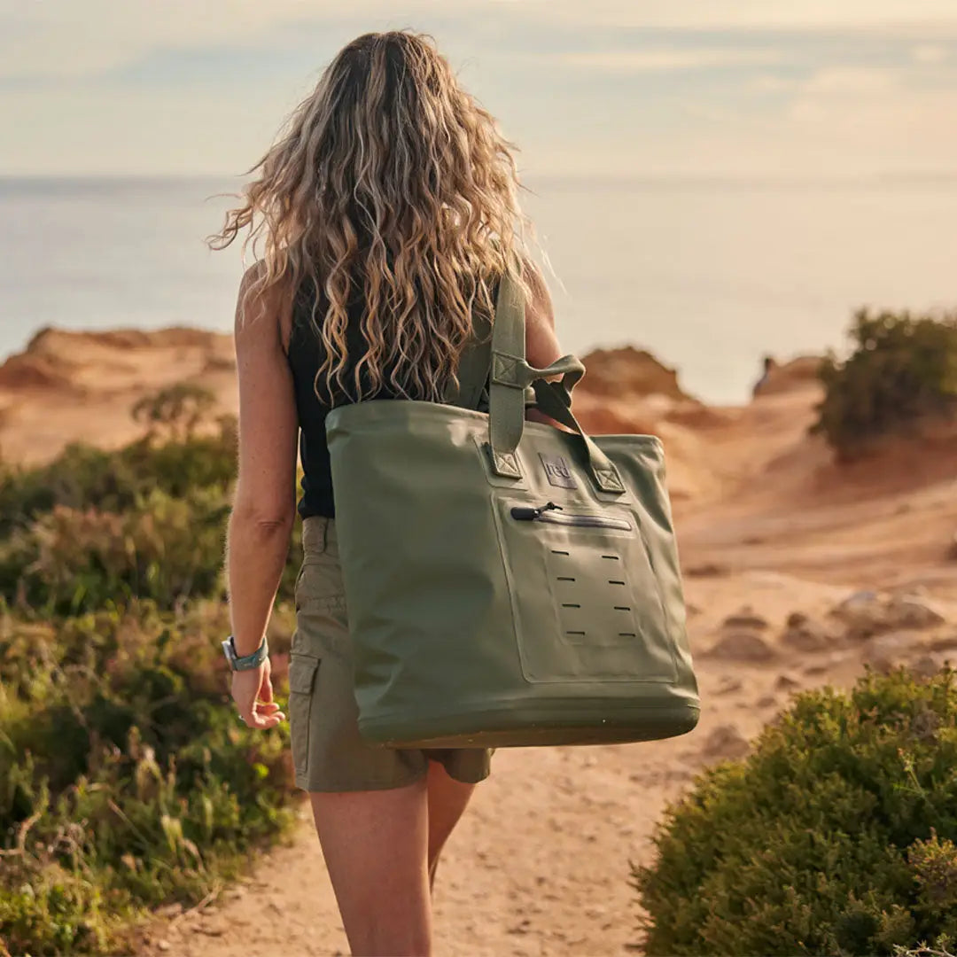 Person with curly blonde hair carrying a stylish green waterproof tote with sleek welded seams