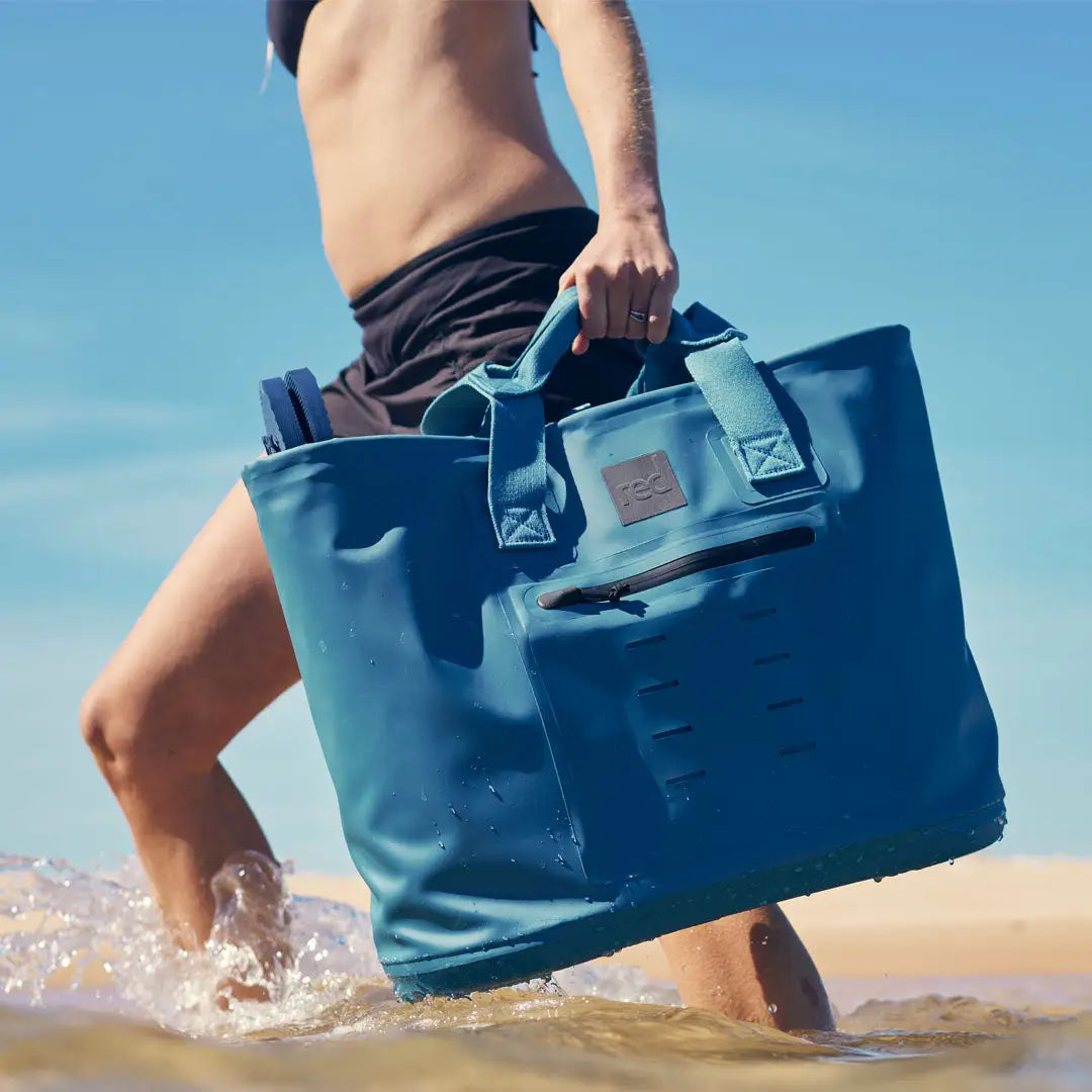 Person walking in shallow water with a Blue Waterproof Tote Bag, perfect for country clothing