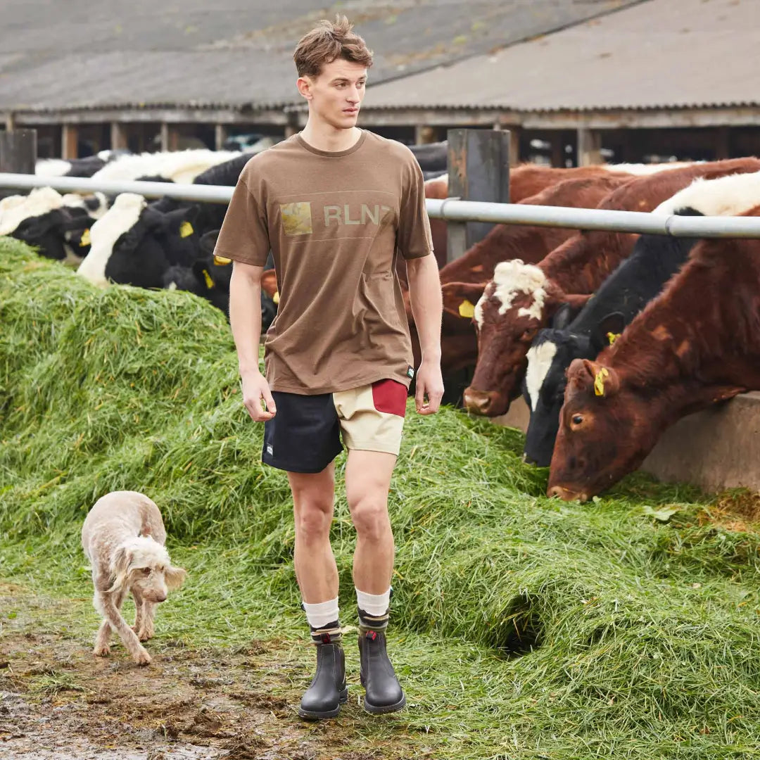 Young man in Ridgeline Backslider Shorts chilling with farm animals on grass