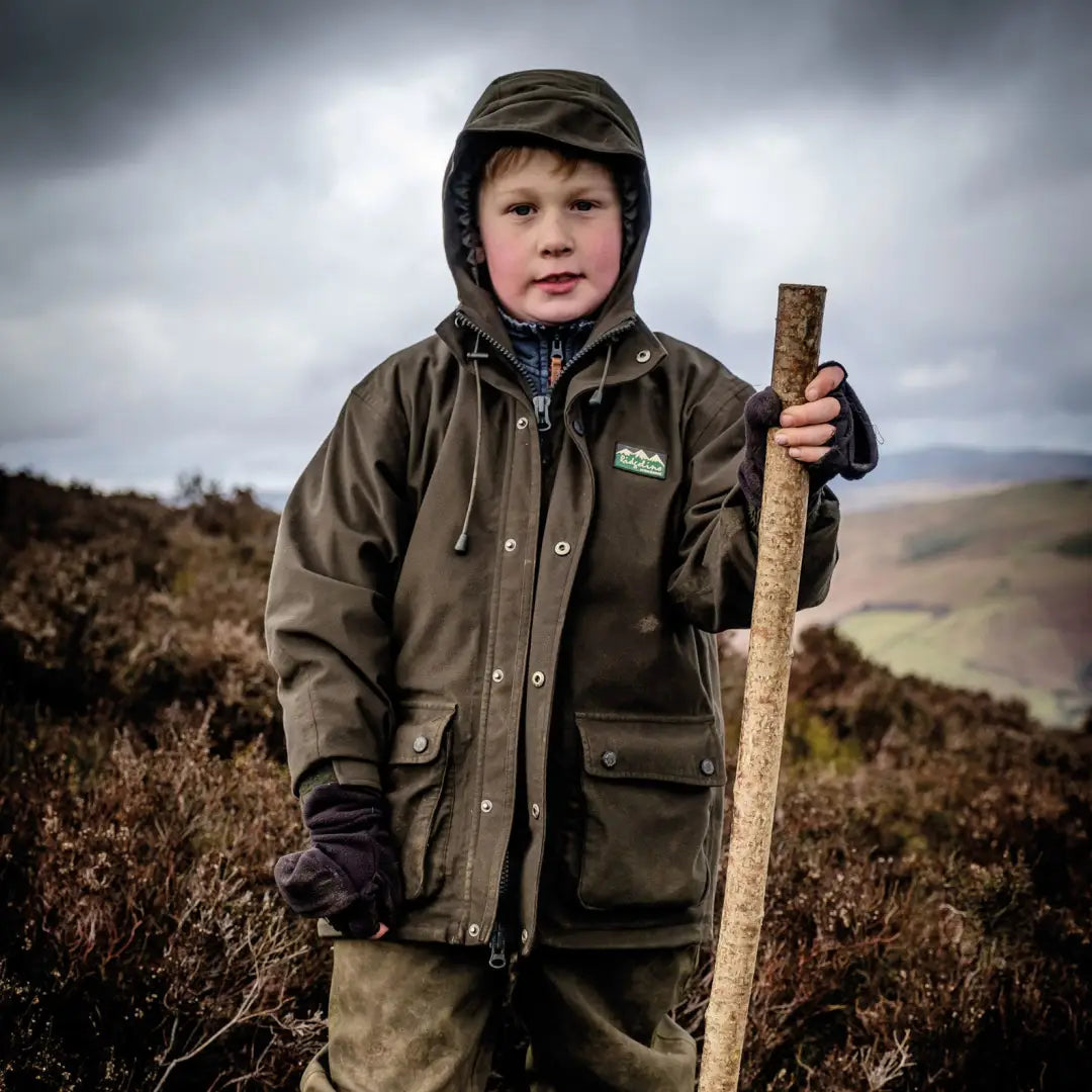 Child in Ridgeline Kids Spiker Jacket exploring rural landscape with walking stick