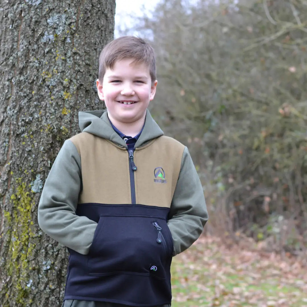 Smiling child in Ridgeline Kids Tribe Hoodie by a tree, showing off a great hoodie