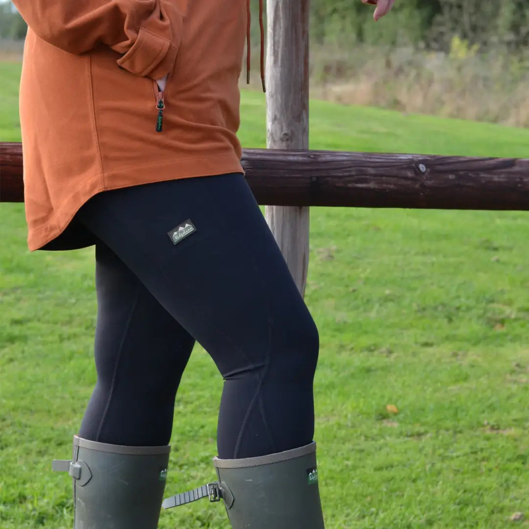 Dark blue Ridgeline Ladies Infinity Leggings styled with green boots and an orange top