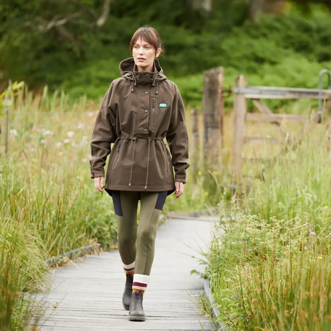 Woman in a large waterproof brown jacket on a path, perfect for country clothing and hunting