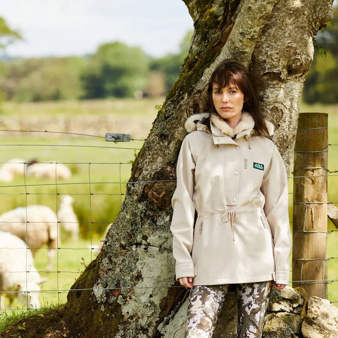 Woman in beige jacket leaning on tree, showcasing the Monsoon Nordic Smock style