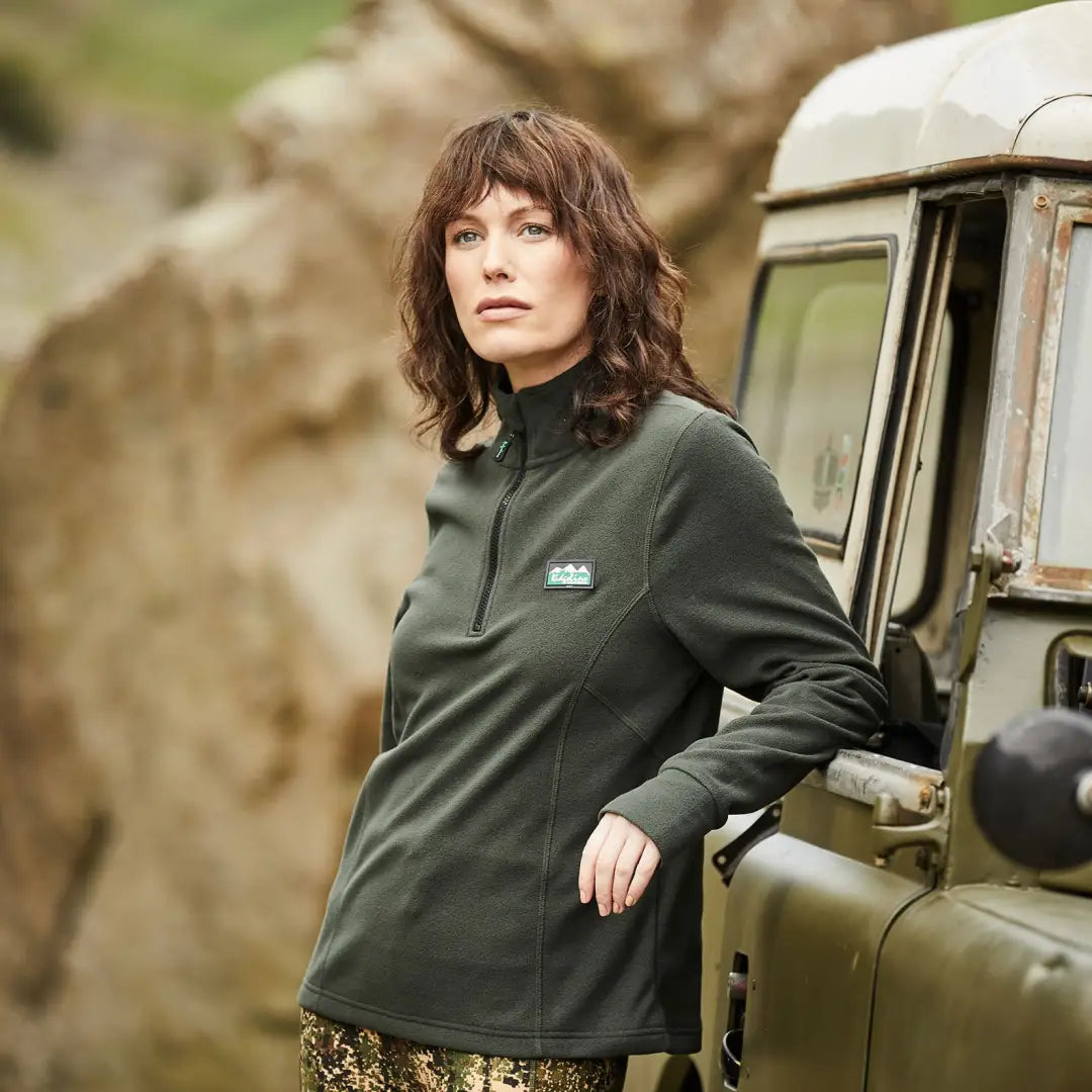 Woman in a dark green jacket by a vehicle, perfect for country clothing and outdoors