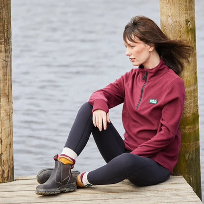 Woman in burgundy fleece on dock, perfect for country clothing and outdoor adventures