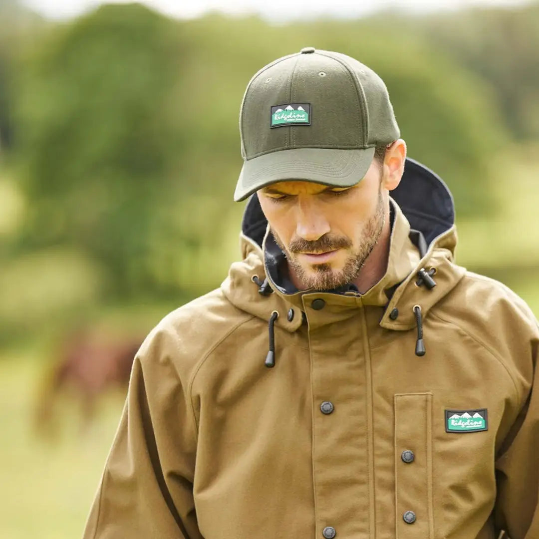 Man in a tan jacket and gray Monsoon Classic Cap Deep with logo