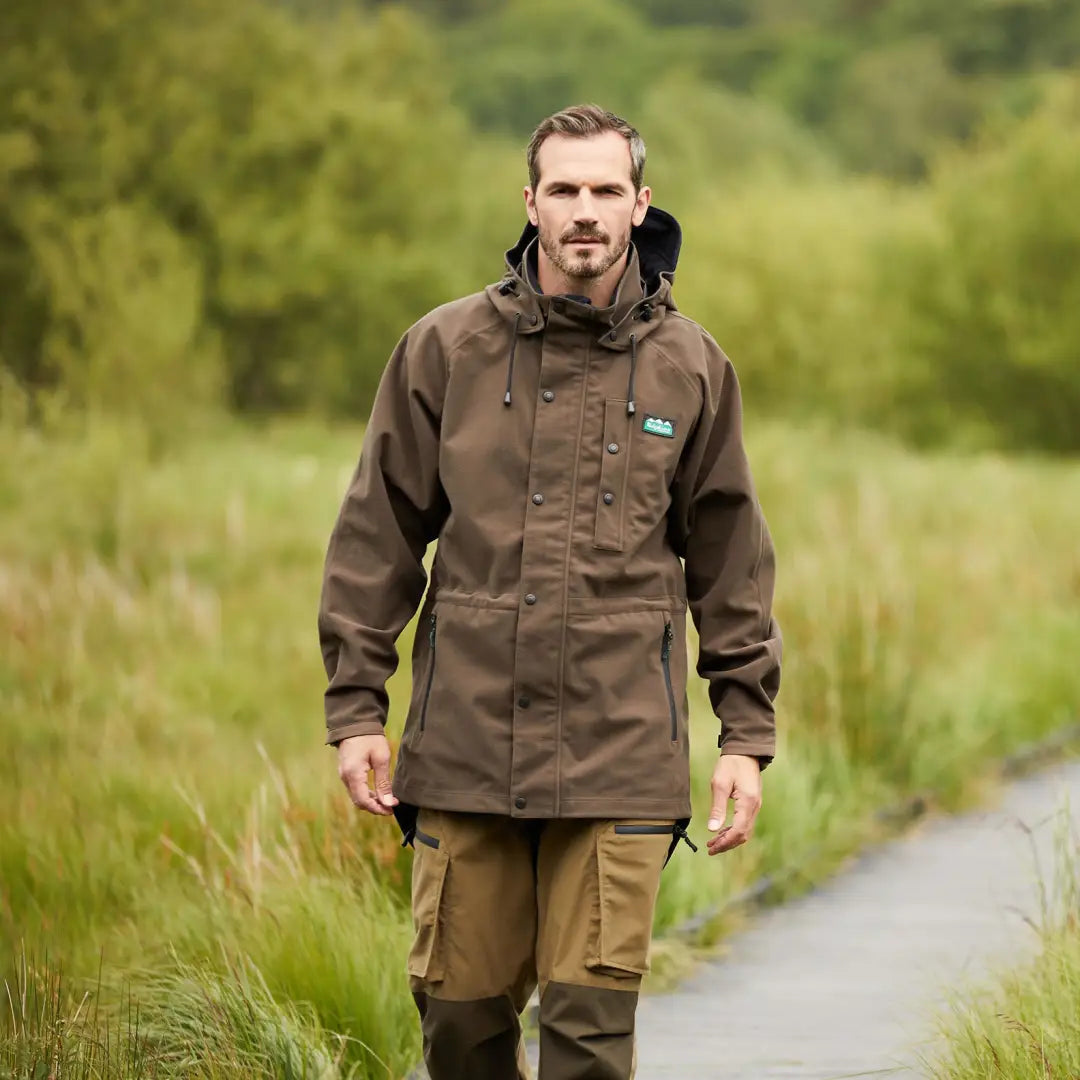 Man in a brown Ridgeline Monsoon Classic Waterproof Jacket hiking on a trail