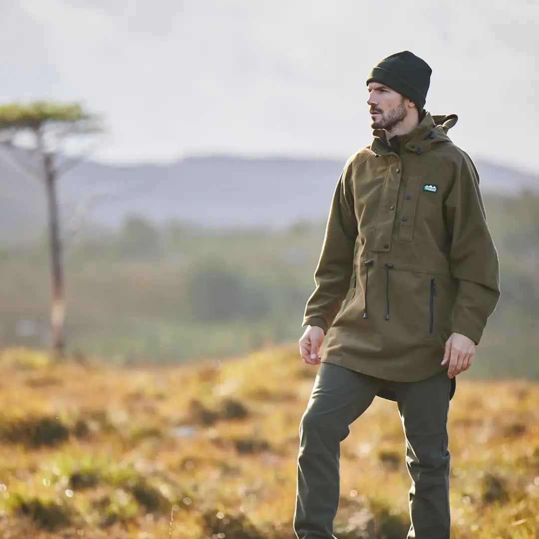 Man in an olive green jacket and black beanie using Ridgeline Monsoon Classic outdoors