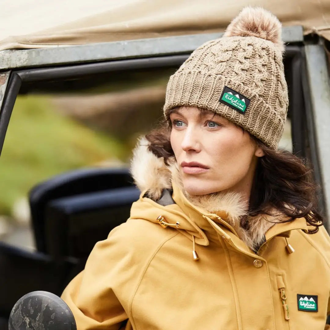 Woman in a yellow jacket rocking a Nordic Fleck Bobble Hat for a cozy style