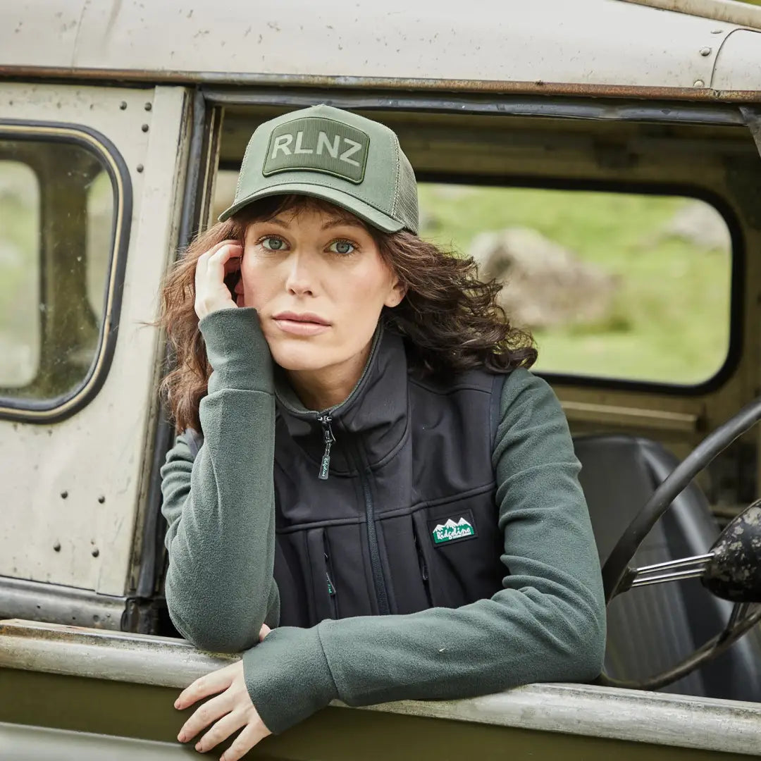 Woman in a green RLNZ Trucker Cap sitting in a vehicle, stylish and casual vibes