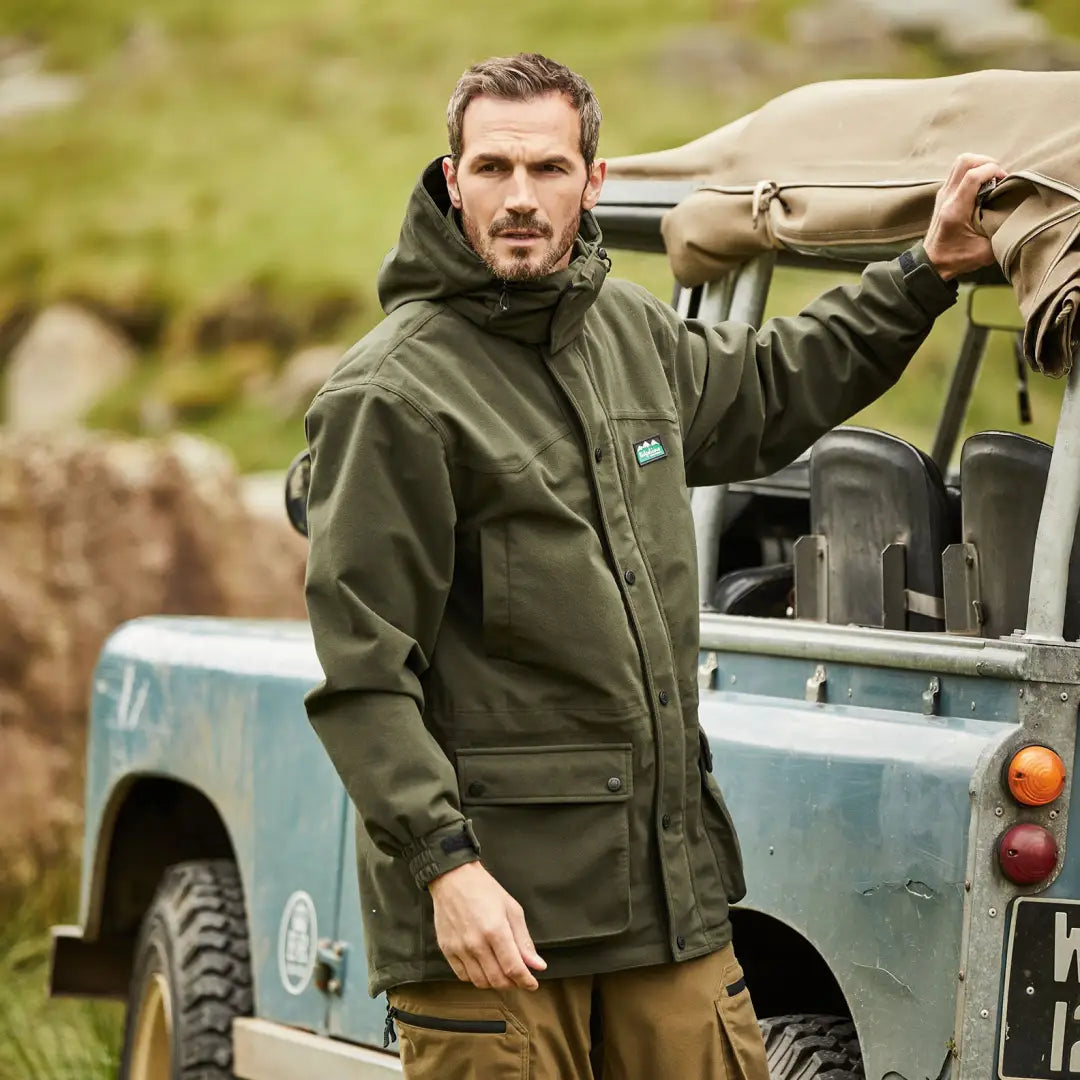 Man in a green jacket standing by a light blue off-road vehicle; Ridgeline Torrent Euro III