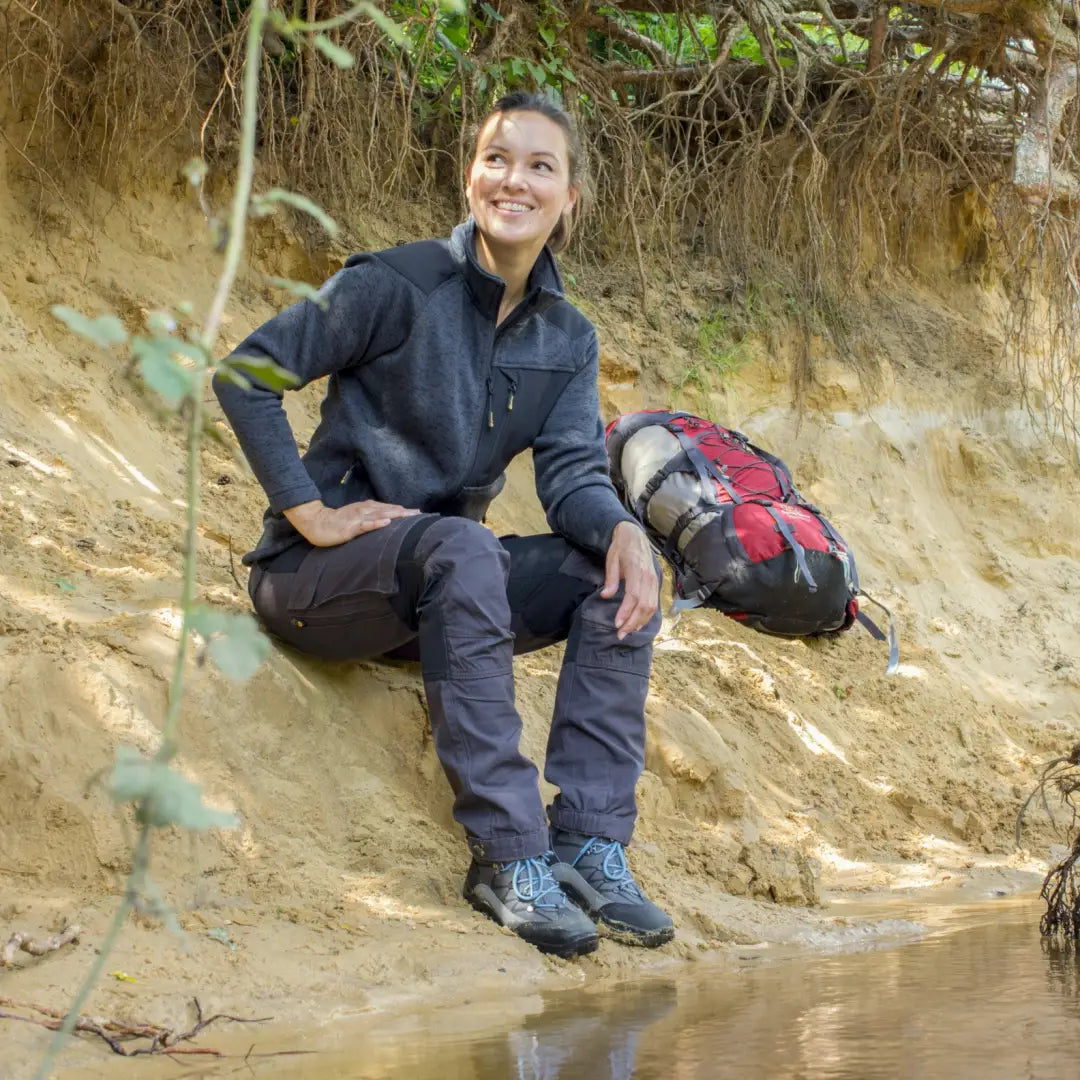 Smiling person on dirt embankment wearing Rovince Womens Flexline Trousers with backpack