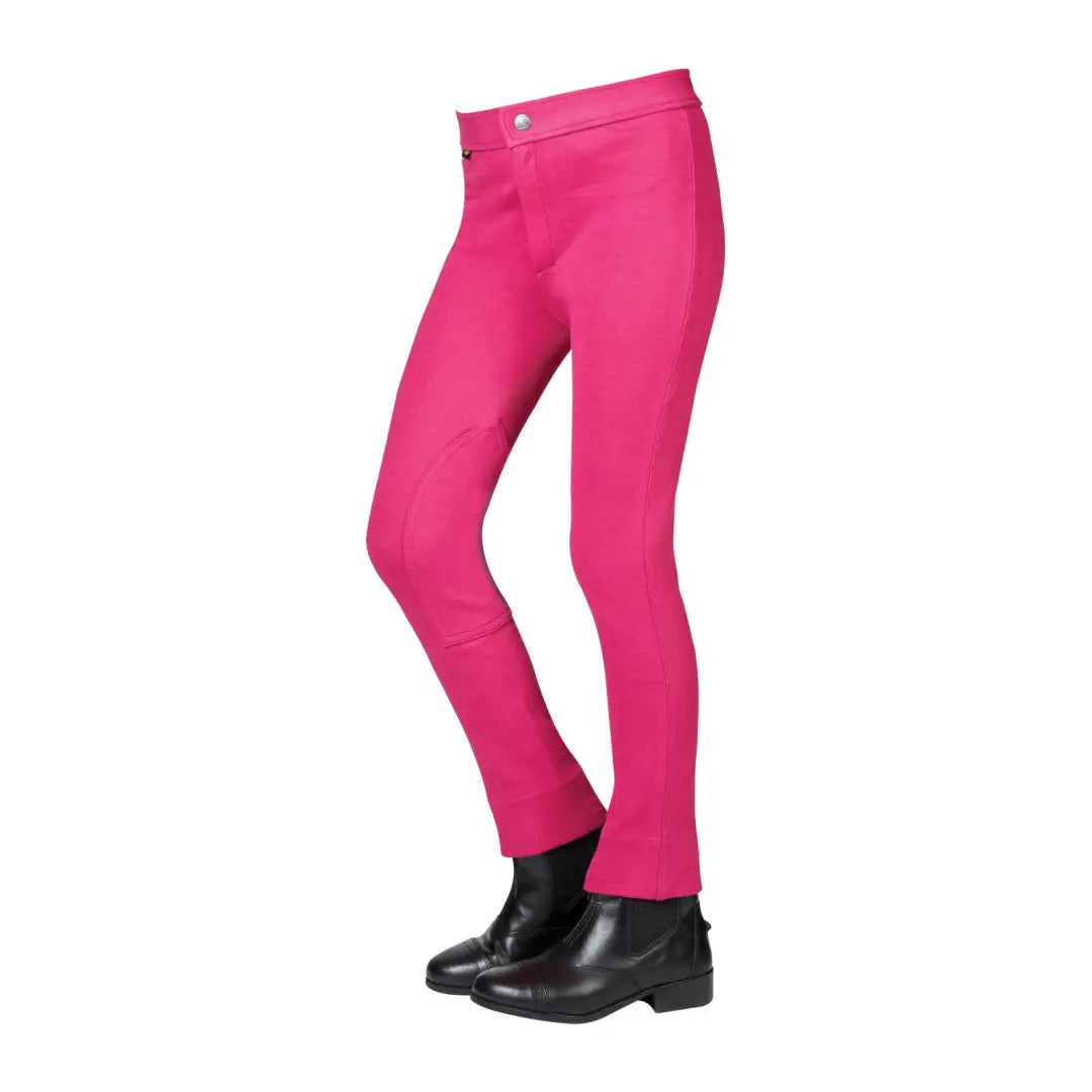 Bright pink Saxon Childs Warm Up Jodhpurs II with stylish black riding boots