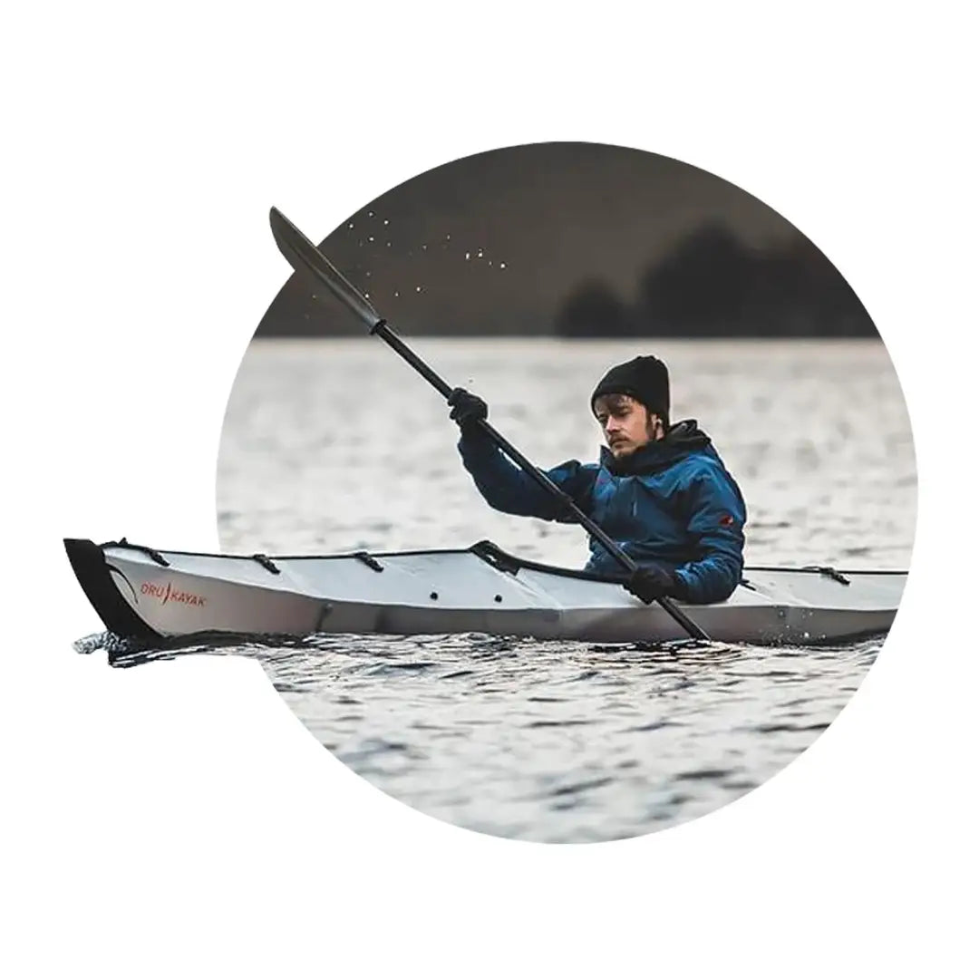 Kayaker in a white kayak on calm water, perfect for outdoor adventures and country clothing