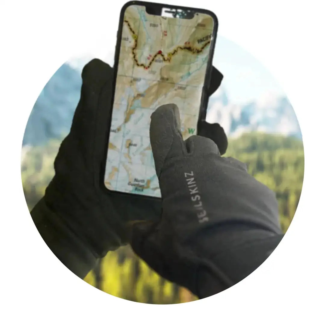 Gloved hand holding a smartphone with a topographic map wearing Sealskinz Harling Glove