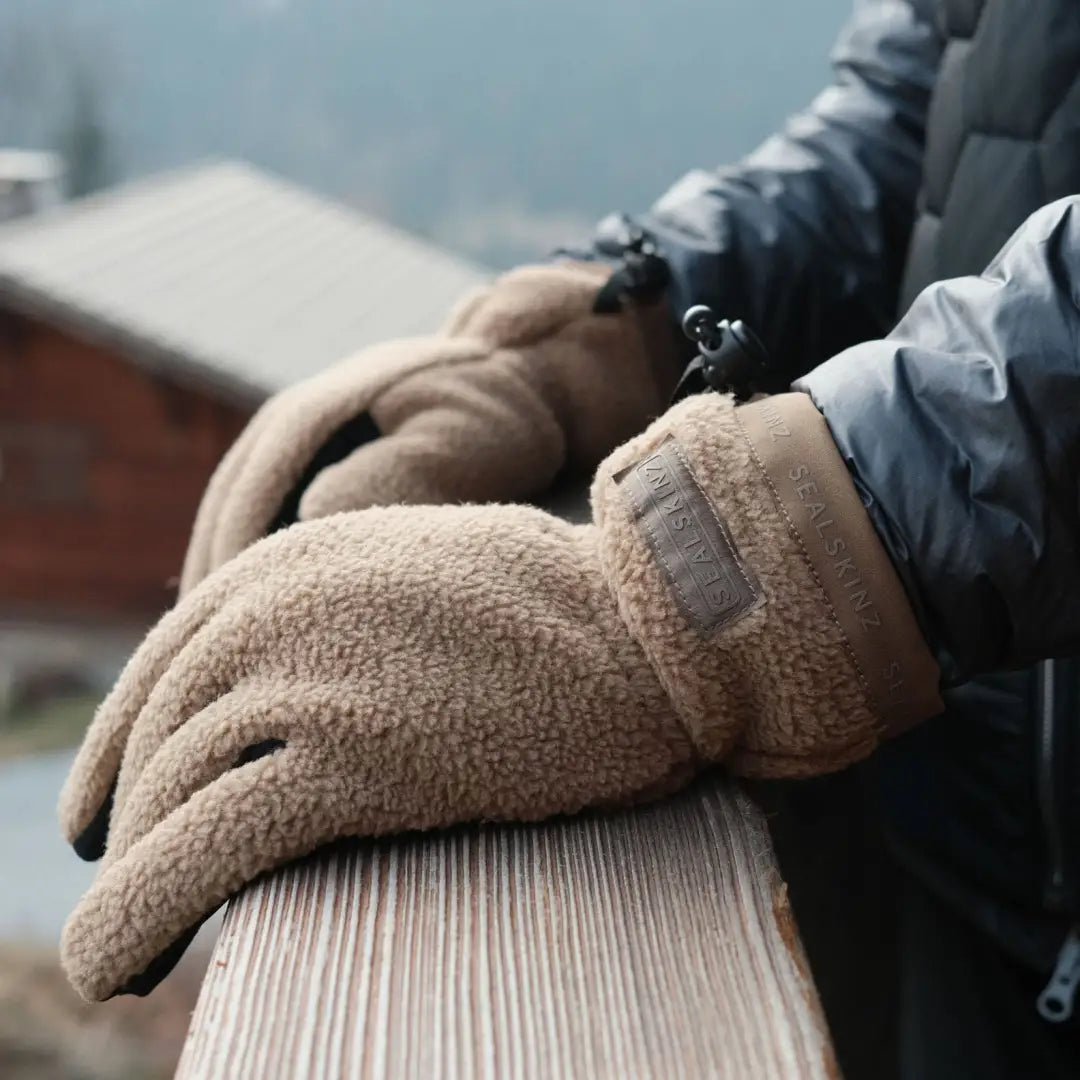 Warm, fuzzy Sealskinz Hoveton Fleece Gloves resting on a wooden surface for country clothing