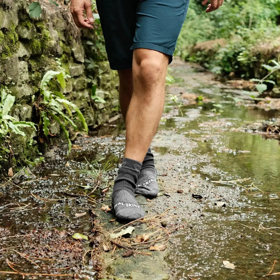 Person in Gray water shoes by a stream wearing Raynham Waterproof Sock for wet adventures