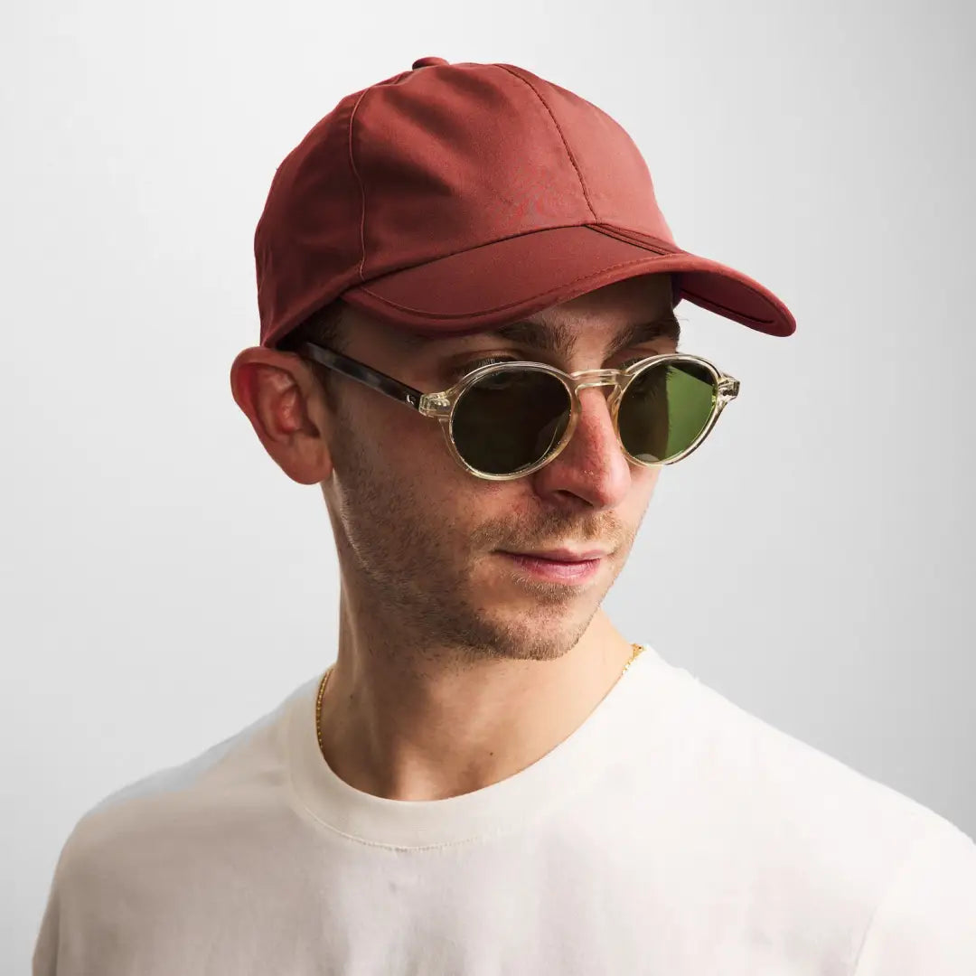 Person in a red baseball cap and round sunglasses enjoying the outdoors with Sealskinz Salle Cap