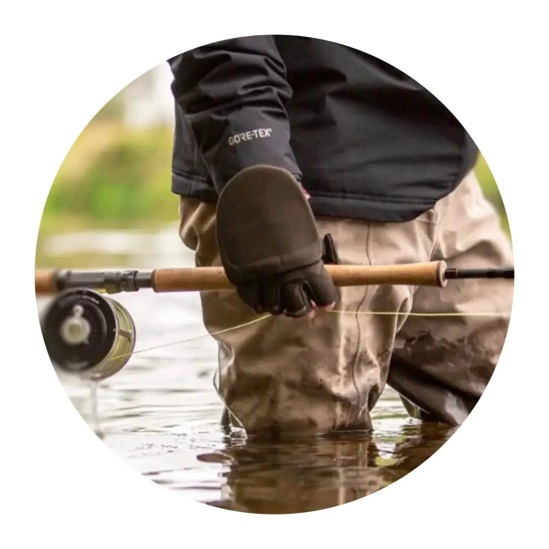 Person in water holding a fly fishing rod wearing lightweight windproof mitt from Sealskinz