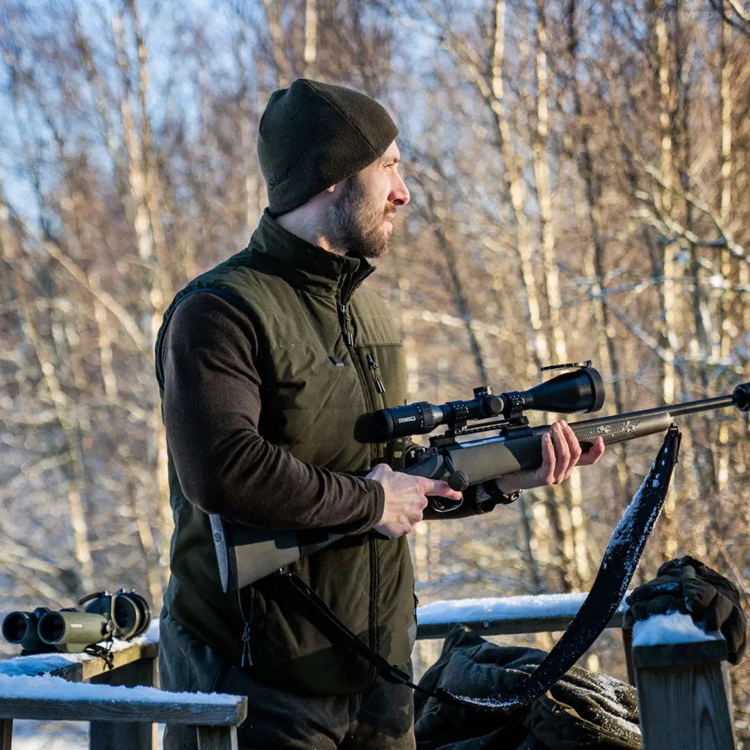 Person in winter gear holding a rifle with scope while wearing Celsius Heat Waistcoat