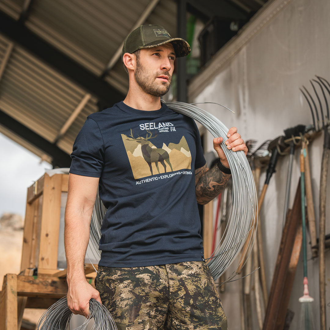 Man in Seeland Fragment T-Shirt and camouflage shorts ready for outdoor hunting adventures