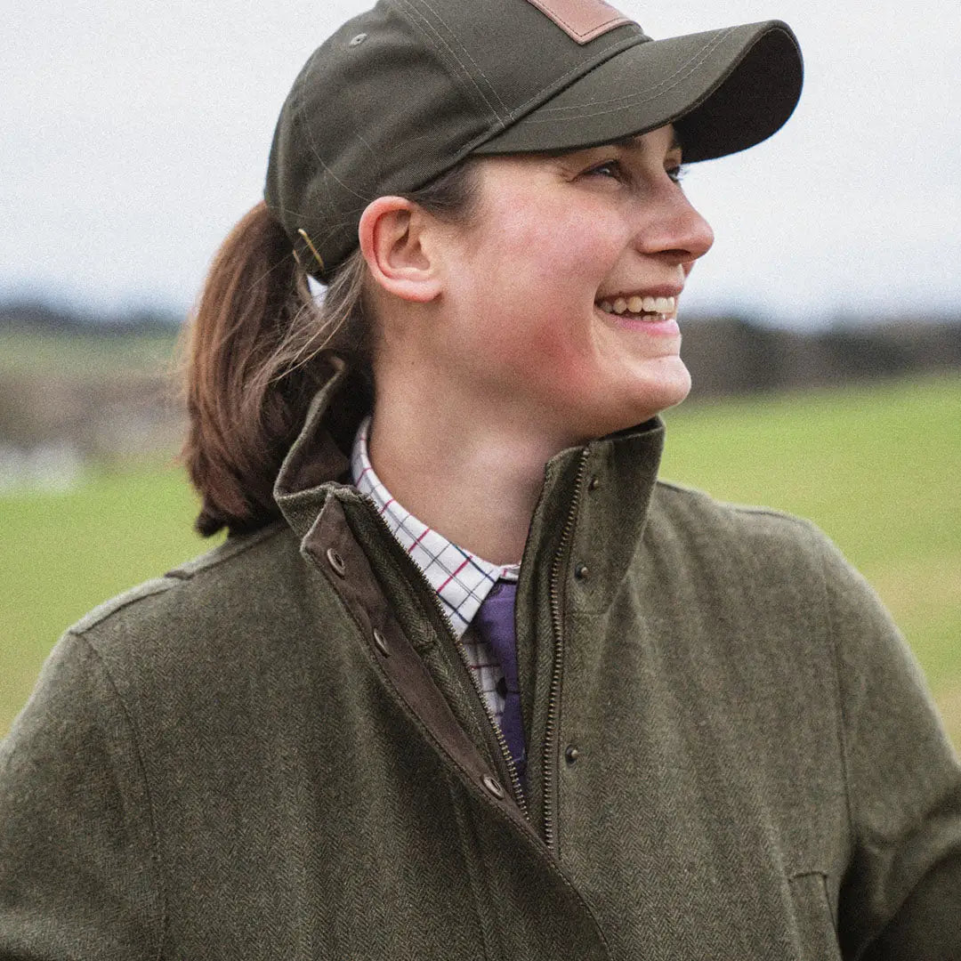 Smiling person in a green cap and jacket outdoors wearing Seeland Hillside Harriet Jacket