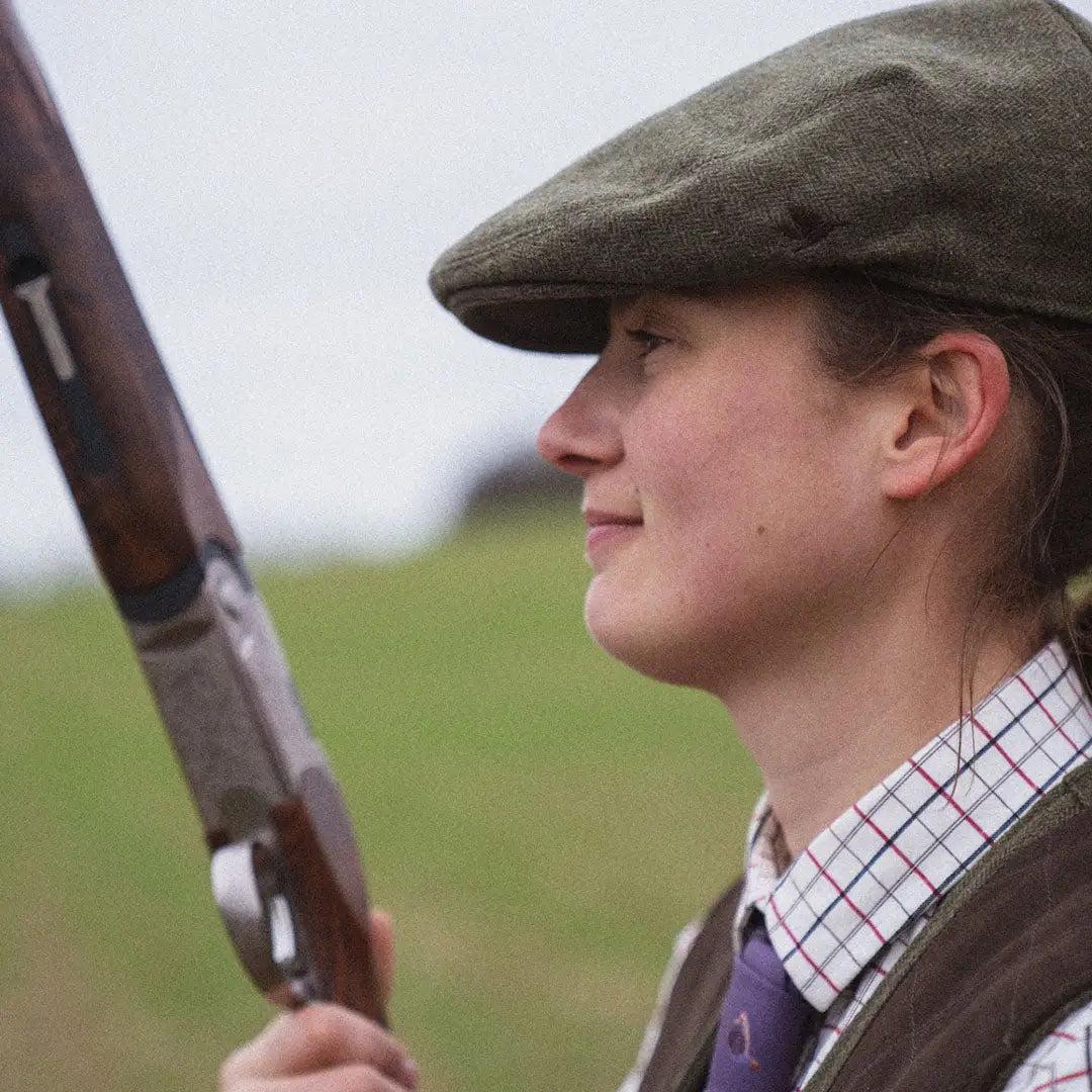 Person in a flat cap holding a shotgun, stylish in a Seeland Hillside Sixpence Hat