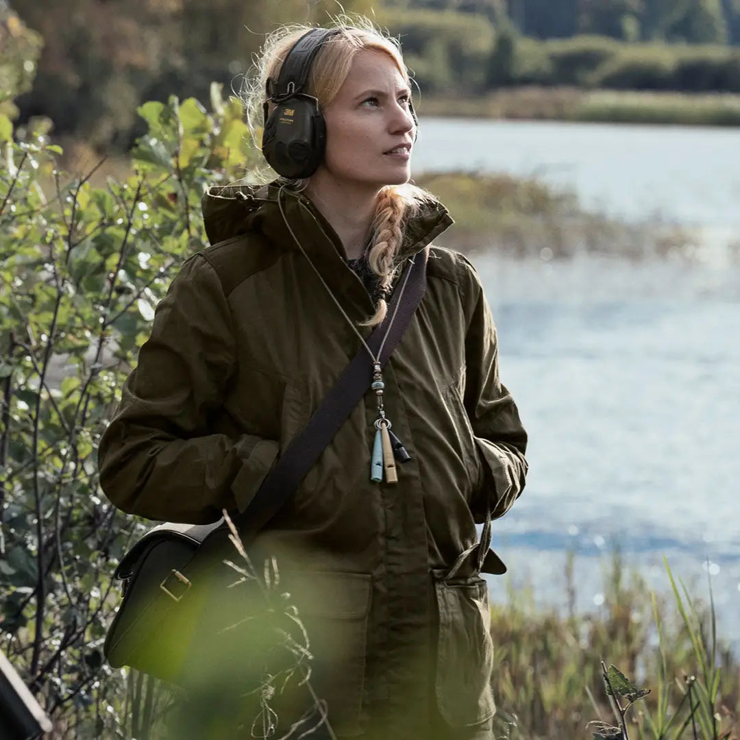 Woman in a green Seeland Key-Point Kora Jacket wearing headphones outdoors