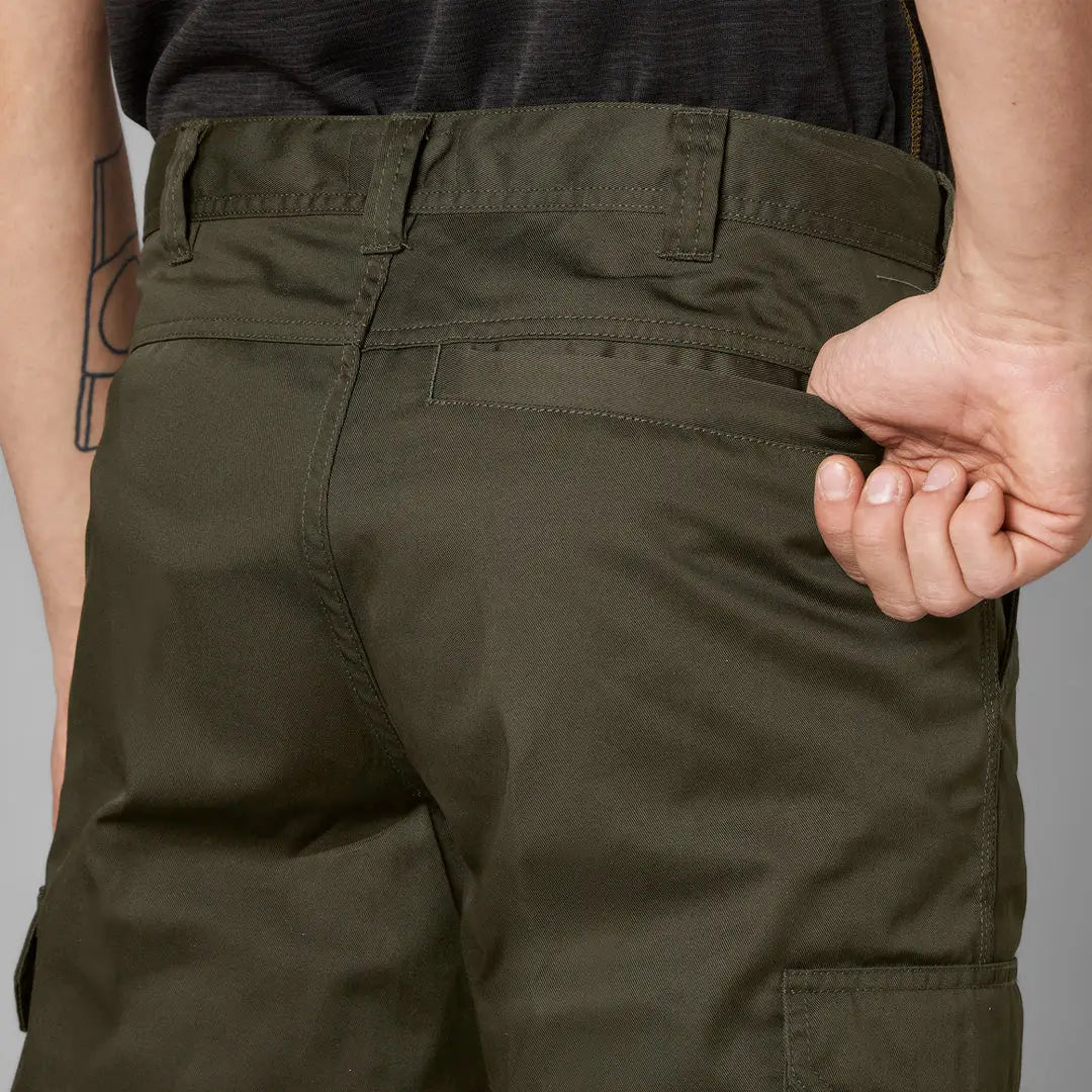 Hand pulling the waistband of Olive Green Seeland Oak Trousers for a comfy fit