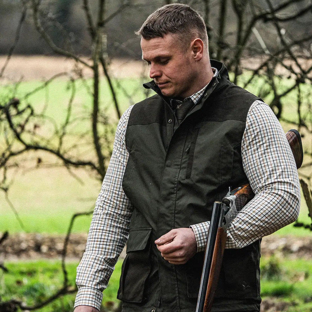 Man in a breathable cotton blend shooting shirt with shotgun in rural outdoor scene